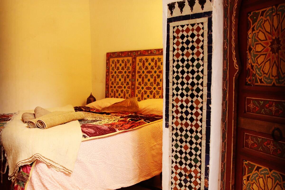 Una habitación con cama, una puerta con diseño y suelo de baldosas.