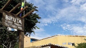 A guest house named 'Biruta' with a wooden gate, a blue potted plant, and an orange building with a tiled roof. - Biruta Guest House (Búzios)
