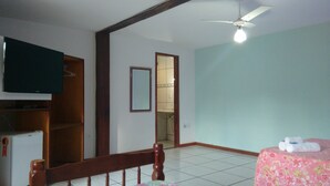 A room with a bed, a TV, a ceiling fan, and a bathroom visible through an open door. - Biruta Guest House (Búzios)