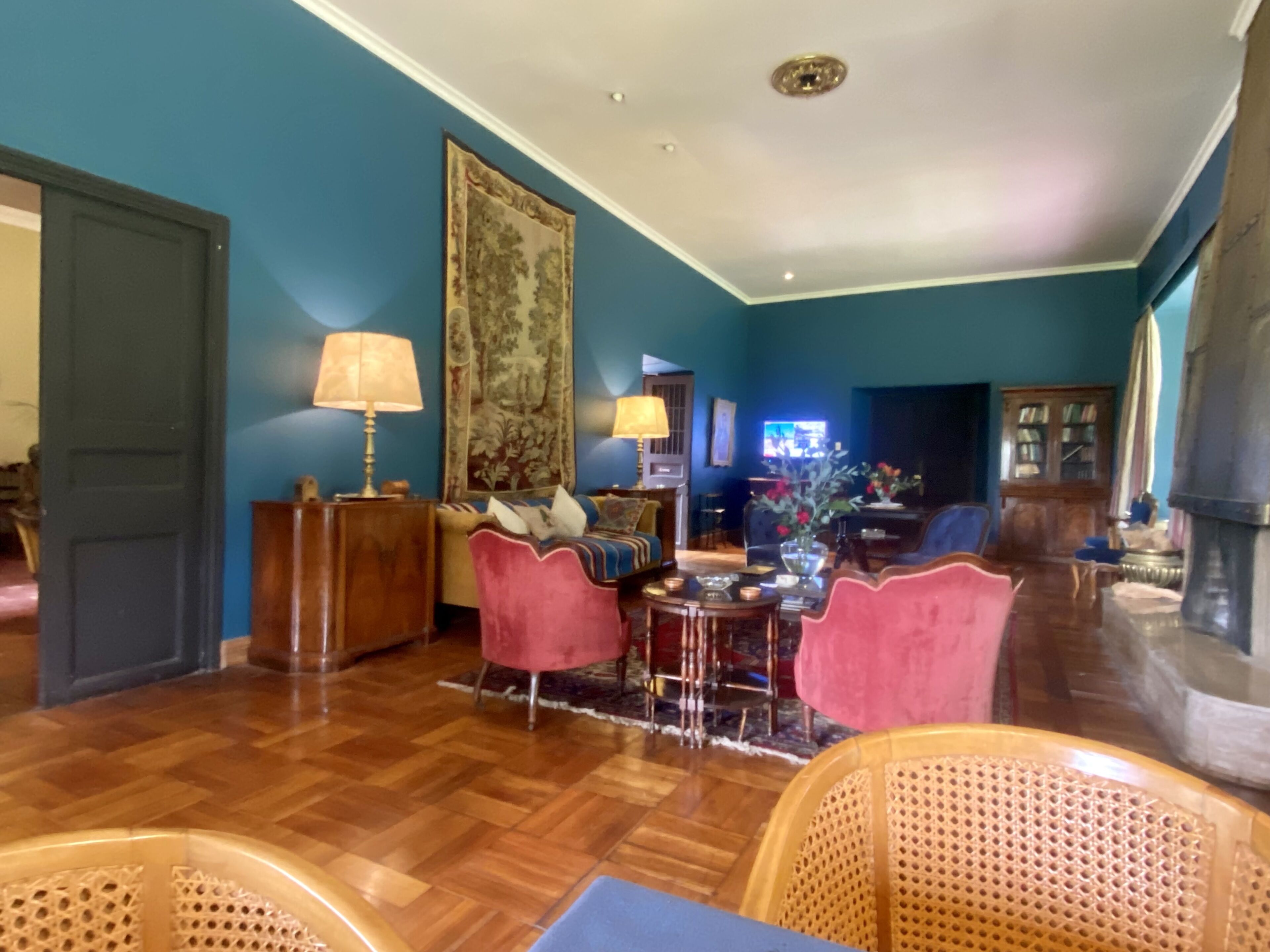 Una sala de estar con piso de madera, un sofá, dos sillones, una mesa de centro y un televisor.