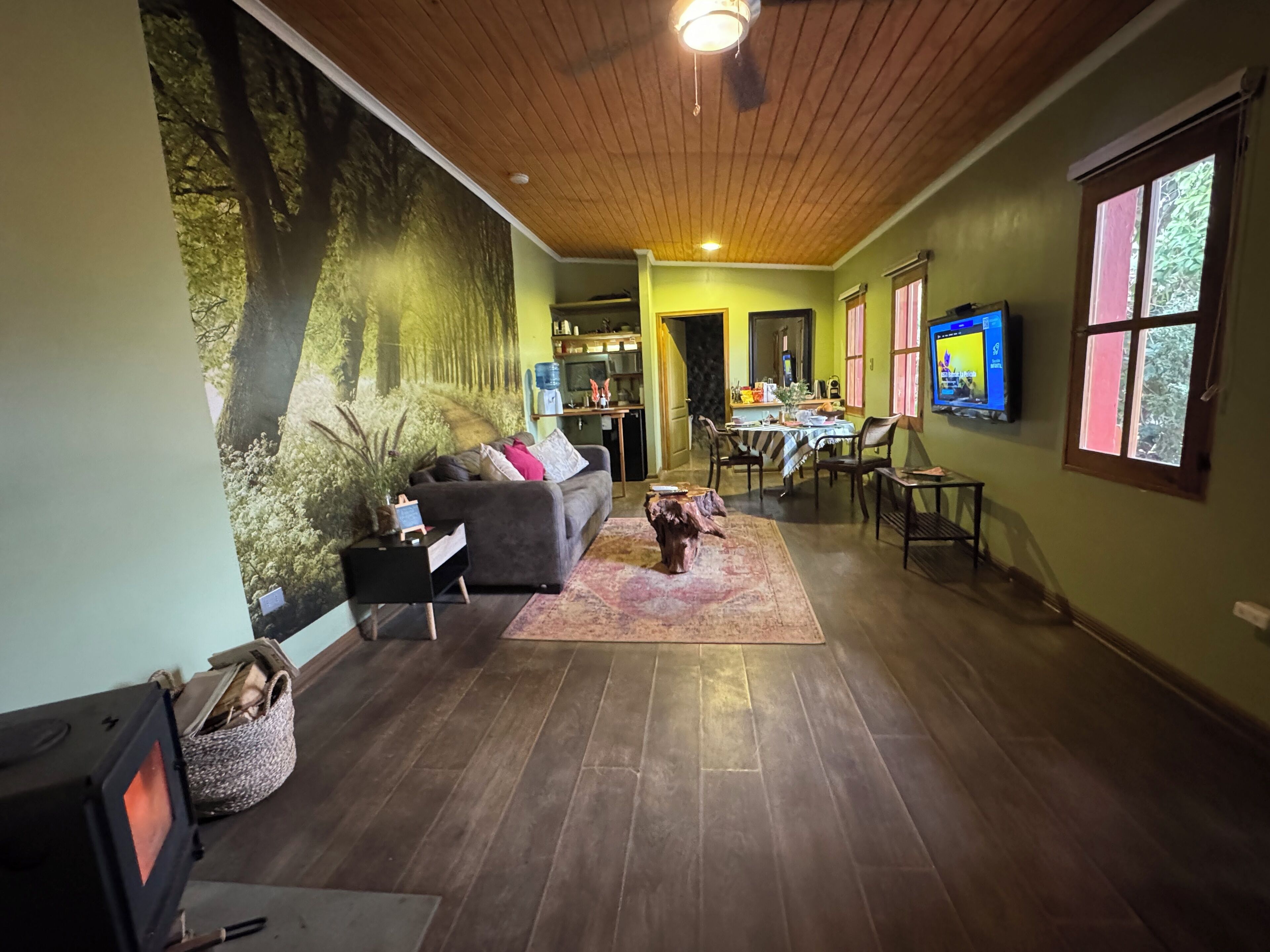 A living room with a large mural, a sofa, a coffee table, and a dining area with chairs and a table.