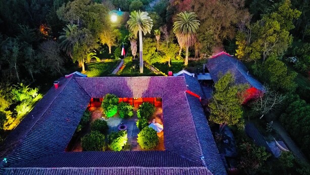 An aerial view of a traditional building with a tiled roof, surrounded by lush greenery and palm trees. - Casona Lo Aguirre Hotel y Convenciones (Talagante)