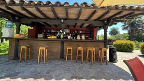 An outdoor bar area with a tiled floor, wooden stools, and a bar counter stocked with bottles. - Casona Lo Aguirre Hotel y Convenciones (Talagante)