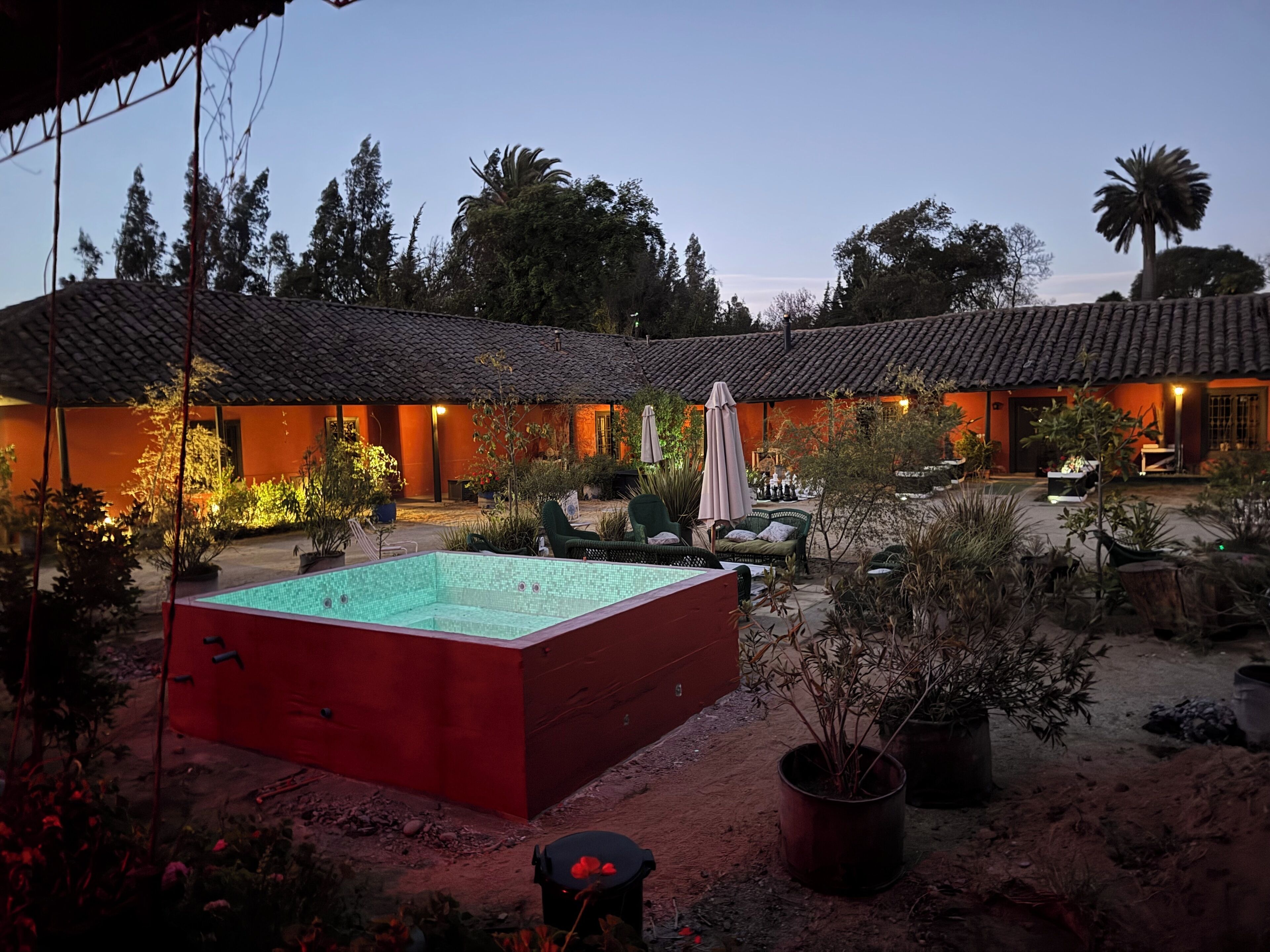 Un patio con piscina, mobiliario exterior y un edificio con techo de tejas.