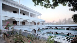 A multi-story building with a central courtyard, featuring a white exterior, multiple balconies, and a small bridge. - Hill Palace Resort (Bandarban)