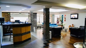 Un hall d’entrée avec un comptoir de réception, un espace salon et un écran de télévision.