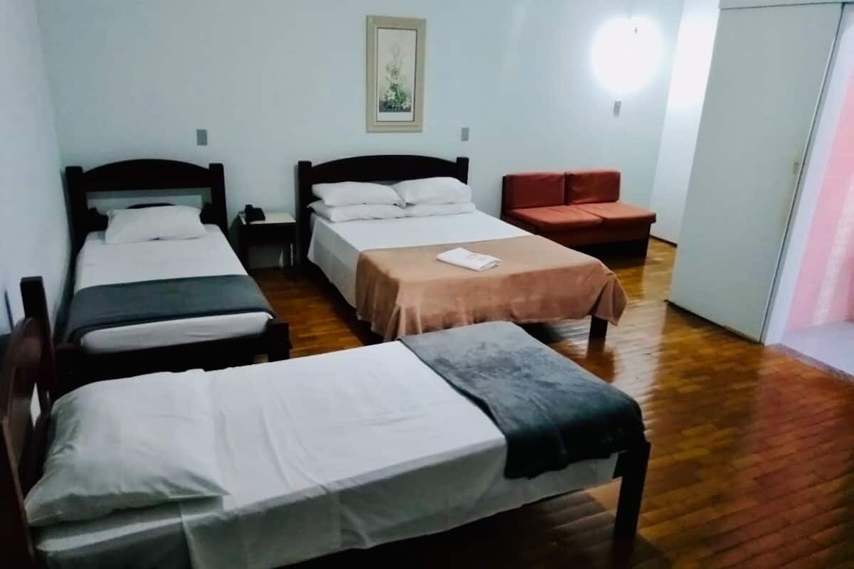 Una habitació amb tres llits, una taula petita i una cadira.