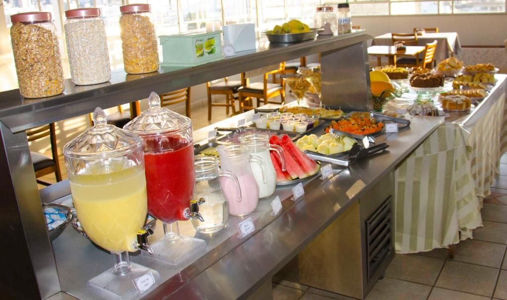 A buffet with various food items and drinks, including jars of condiments and a selection of beverages.