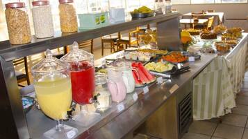 A buffet with various food items and drinks, including jars of condiments and a selection of beverages.