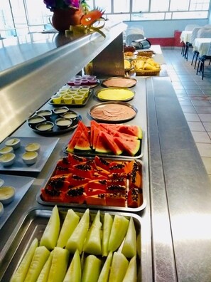 Un bufé con diversas opciones de comida, incluyendo sandía, yogur y otras frutas.