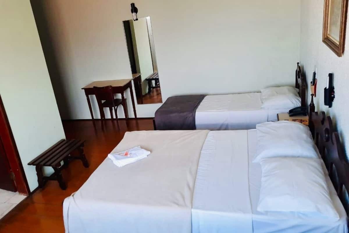 Habitació d'hotel amb dos llits, una taula, una cadira i un mirall.