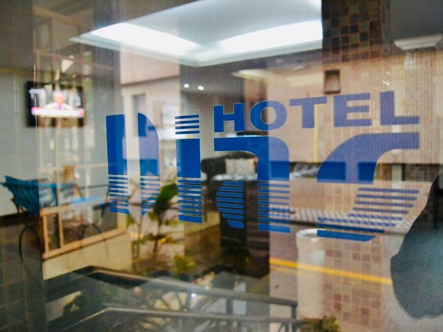 A hotel interior with a reception area, a staircase, and a view of the lobby.
