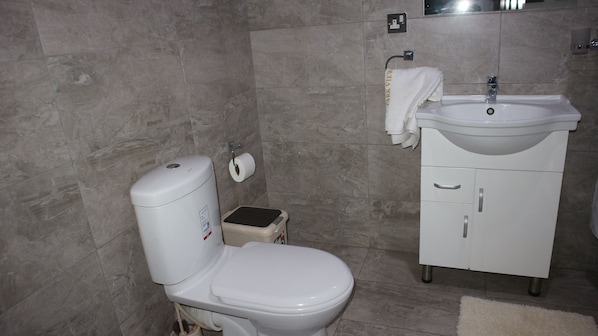 Un baño con inodoro, lavamanos y un perchero para toallas.