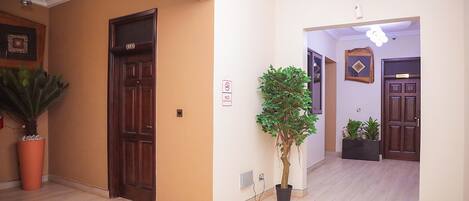 A hallway with wooden doors, potted plants, and a 'No Smoking' sign.