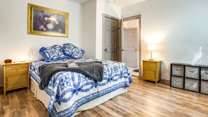 Een slaapkamer met een bed, nachtkastjes, een plafondventilator, een deur, een lamp en een wandmeubel.