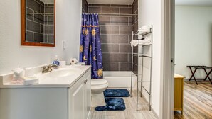 Een badkamer met een wit wastafel, toilet, bad en een douchegordijn met een sterren-en-maanmotief.