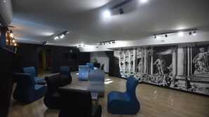 A modern lounge area with contemporary seating, a large mural, and recessed lighting.