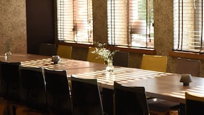 A dining area with a long table, chairs, and a vase with flowers.