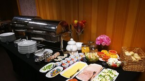 A buffet table with various food items, including salads, meats, and fruits.