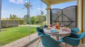 A patio with a table set for two, a view of a garden, and a lattice screen.