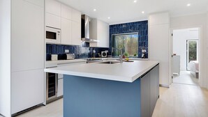A modern kitchen with a central island, white cabinetry, and a blue backsplash.