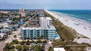 A coastal hotel with multiple floors, a swimming pool, and a beach view. - Sandpiper Oceanfront 5F (Jacksonville Beach)
