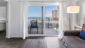 A balcony with a view of the ocean and buildings, a sofa, and a lamp. - Sandpiper Oceanfront 5F (Jacksonville Beach)
