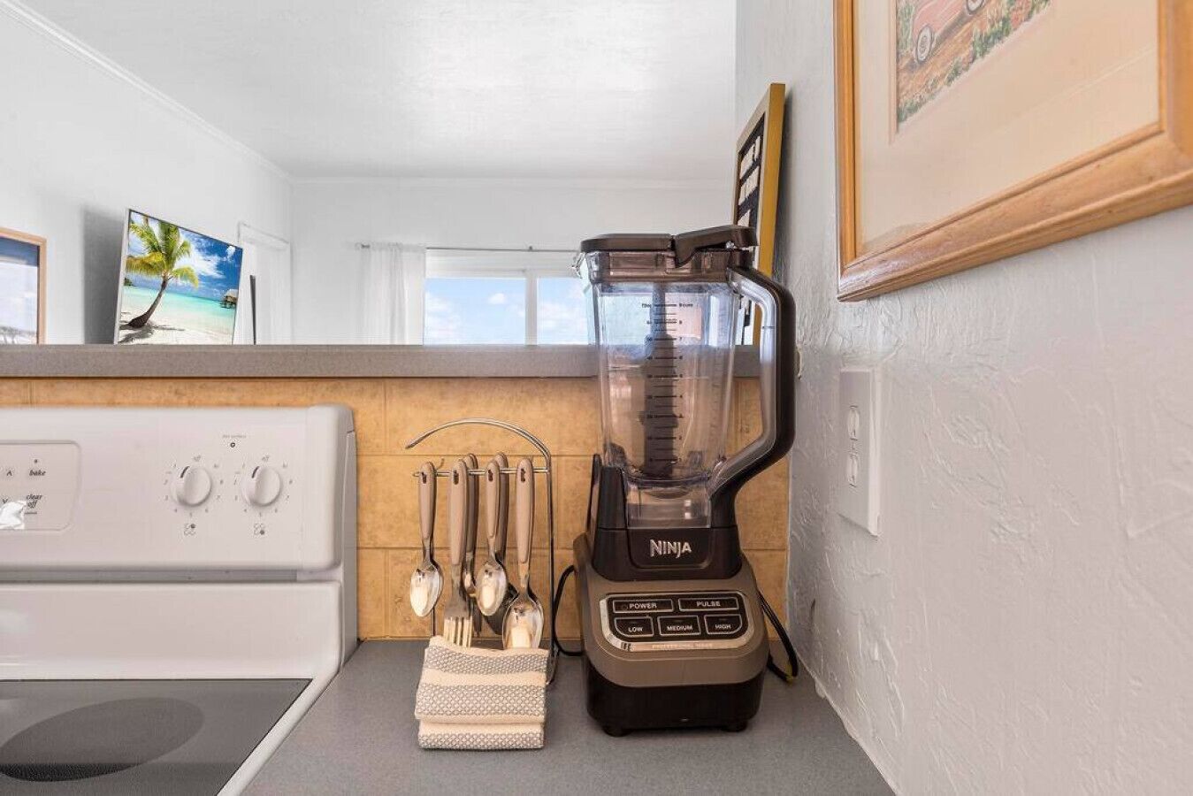 Een keuken met een witte kookplaat, een Ninja blender en een messenhouder.