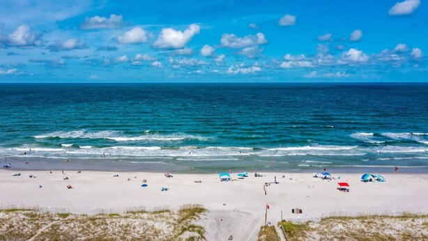 A beach with clear blue water, white sand, and a few umbrellas. - Sandpiper Oceanfront 5F (Jacksonville Beach)