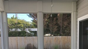 A covered patio with two wicker sofas facing a swimming pool, wooden deck, and a view of a backyard with a wooden fence and trees. -  Cape May Beach- Luxury Delaware Bay Beauty- Heated Pool-Linens (Cape May Beach)