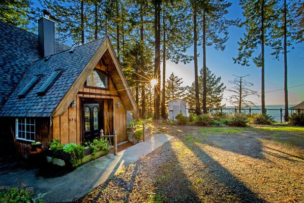 Une cabane en bois avec un toit en pente, une cheminée et une porte d’entrée.