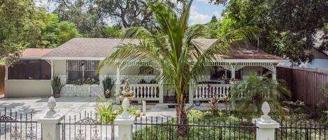 A house with a covered porch, a fountain, and a gated entrance.