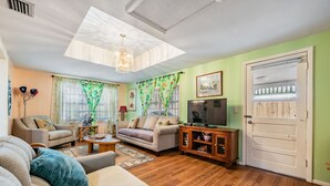 A living room with a sofa, a coffee table, a TV, and a door with a window. - #1 LOCATION  - Walk to Amusement Parks from PERFECT HOME, Great for Families 🏠 (Tampa)