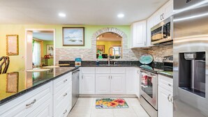 A kitchen with white cabinets, a stainless steel refrigerator, and a tiled backsplash. - #1 LOCATION  - Walk to Amusement Parks from PERFECT HOME, Great for Families 🏠 (Tampa)