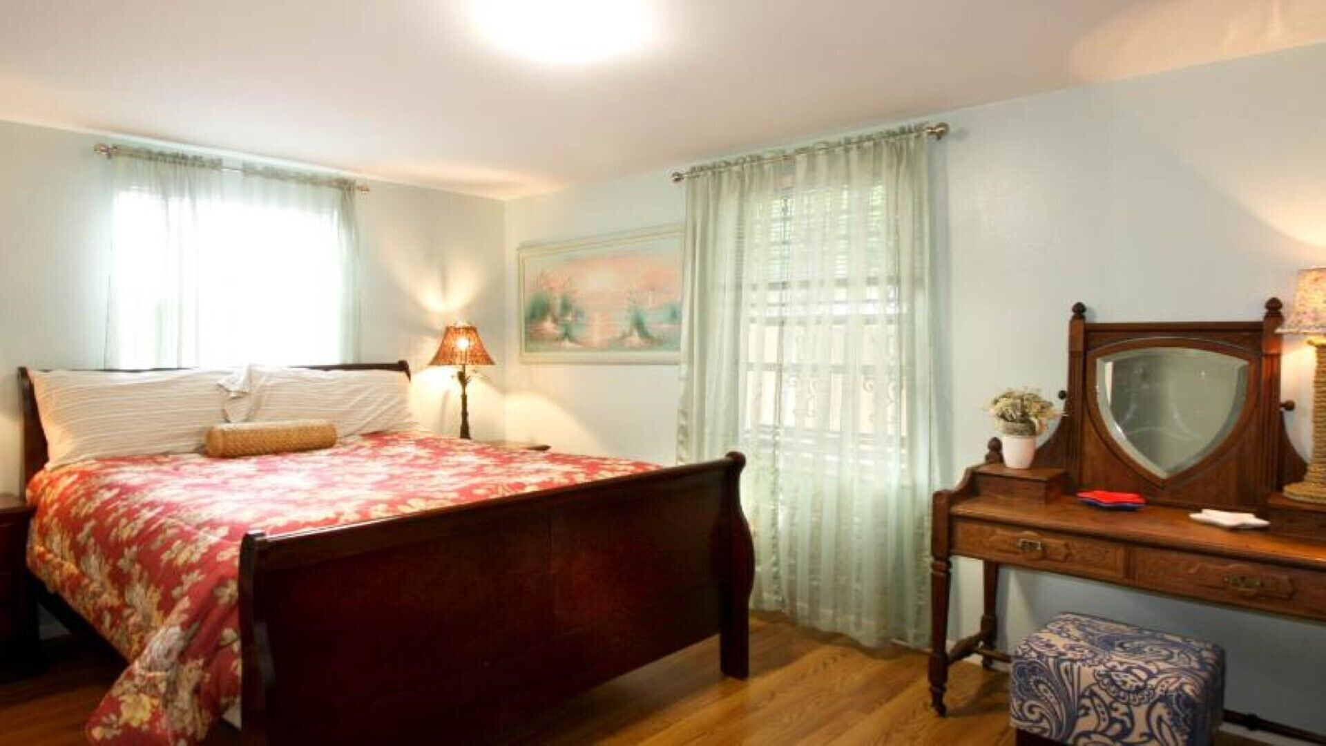 Un dormitorio con cama, cómoda, espejo y lámpara.