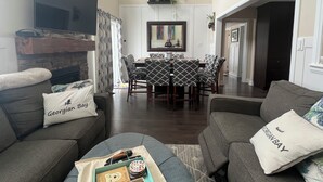 Un salon avec une cheminée, un coin repas et un téléviseur fixé au mur.