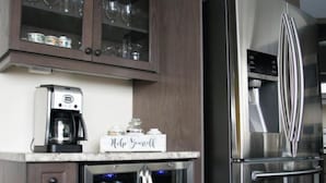 Une cuisine équipée d’un réfrigérateur en acier inoxydable, d’une machine à café et d’un mini-réfrigérateur contenant des boissons.