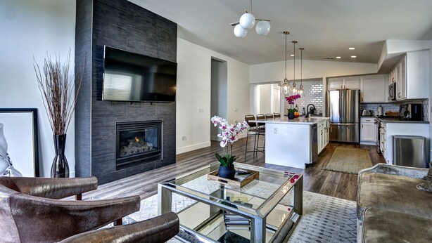 A modern living room with a fireplace, a glass coffee table, and a sofa. - Monthly  1 Story, 3 Bdr Gorgeous Home Summerlin Pet Friendly (Las Vegas)