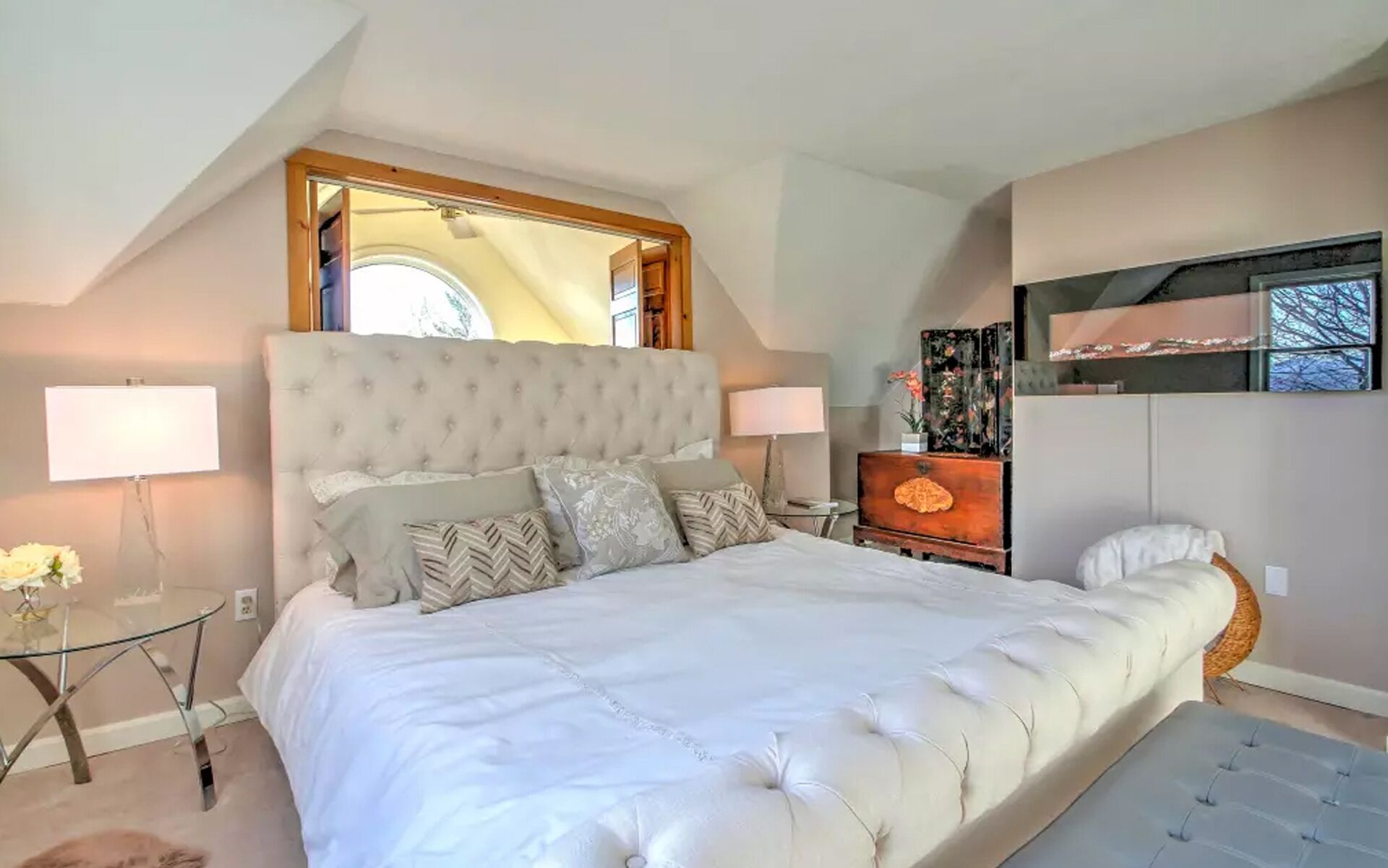 Ein Schlafzimmer mit einem großen Bett, zwei Nachttischen, einem Spiegel über dem Bett, einem Schminktisch und einem an der Wand befestigten Fernseher.