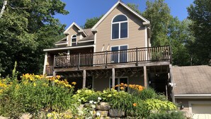 A two-story house with a balcony, surrounded by a garden with various flowers and rocks. - EPIC Mountain View Home : Minutes to Skiing!! (Jackson)