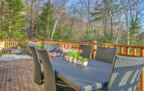 Una terraza al aire libre con mobiliario de mimbre, una mesa con platos, vasos y plantas.