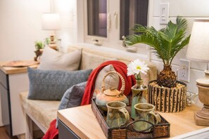 Un salon confortable avec un canapé, une petite table agrémentée d’objets décoratifs et une fenêtre.