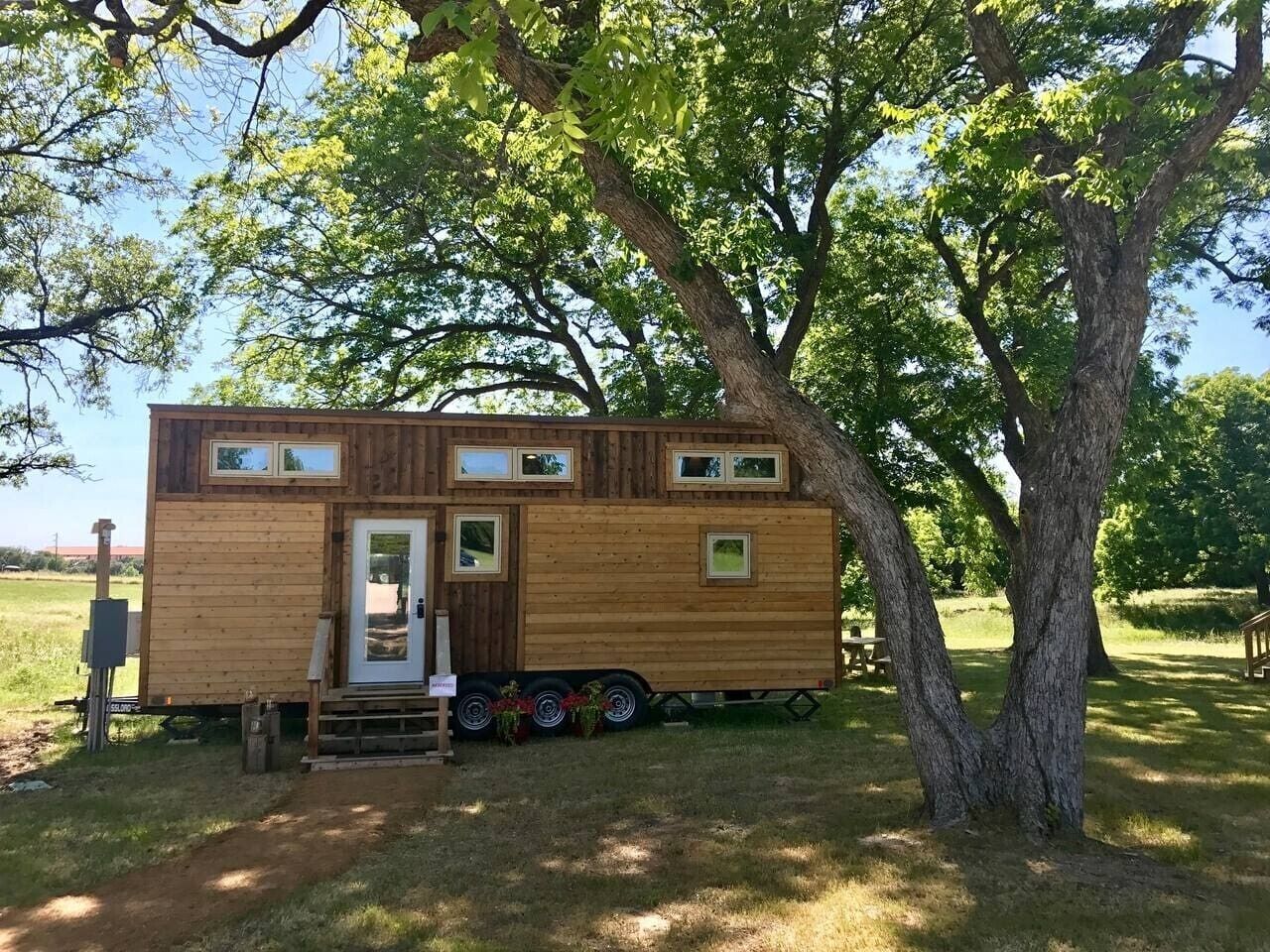 A wooden mobile home with a door, windows, and a small porch area.