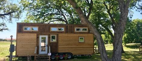 A wooden mobile home with a door, windows, and a small porch area.