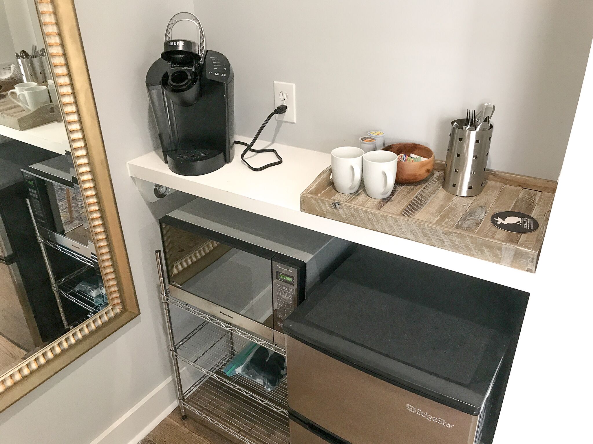 A kitchenette with a coffee maker, two mugs, a toaster, and a microwave.
