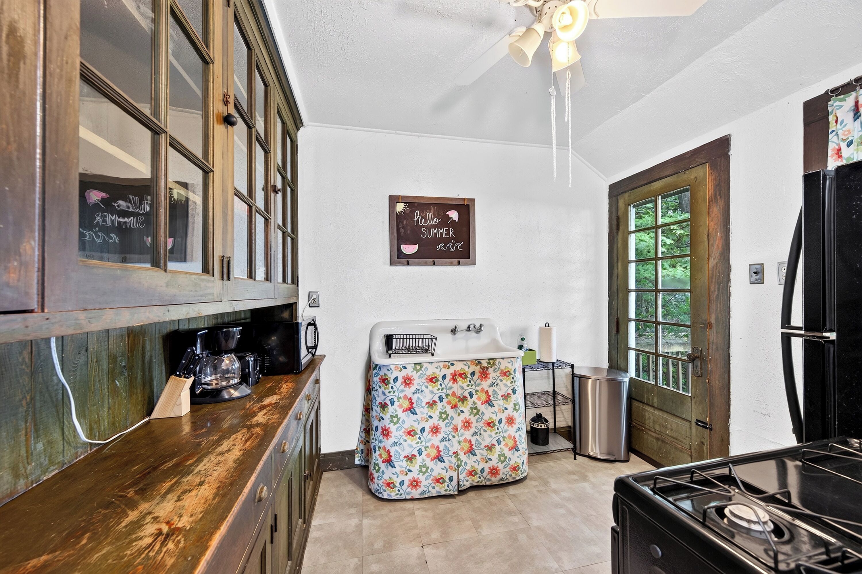 A kitchen with wooden cabinets, a coffee maker, a sink, and a refrigerator.