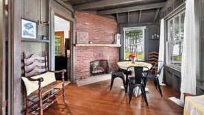 Un interior rústico con chimenea de ladrillo, muebles de madera y vistas a través de una ventana.