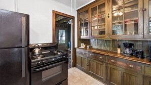Una cocina con estufa negra, armarios de madera y refrigerador.