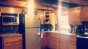 Une cuisine avec des meubles de rangement en bois, un réfrigérateur, un four à micro-ondes et une machine à café.