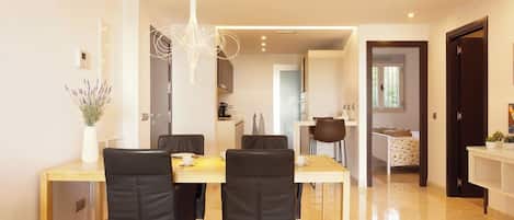 A modern dining area with a long table, four chairs, and a hanging light fixture.